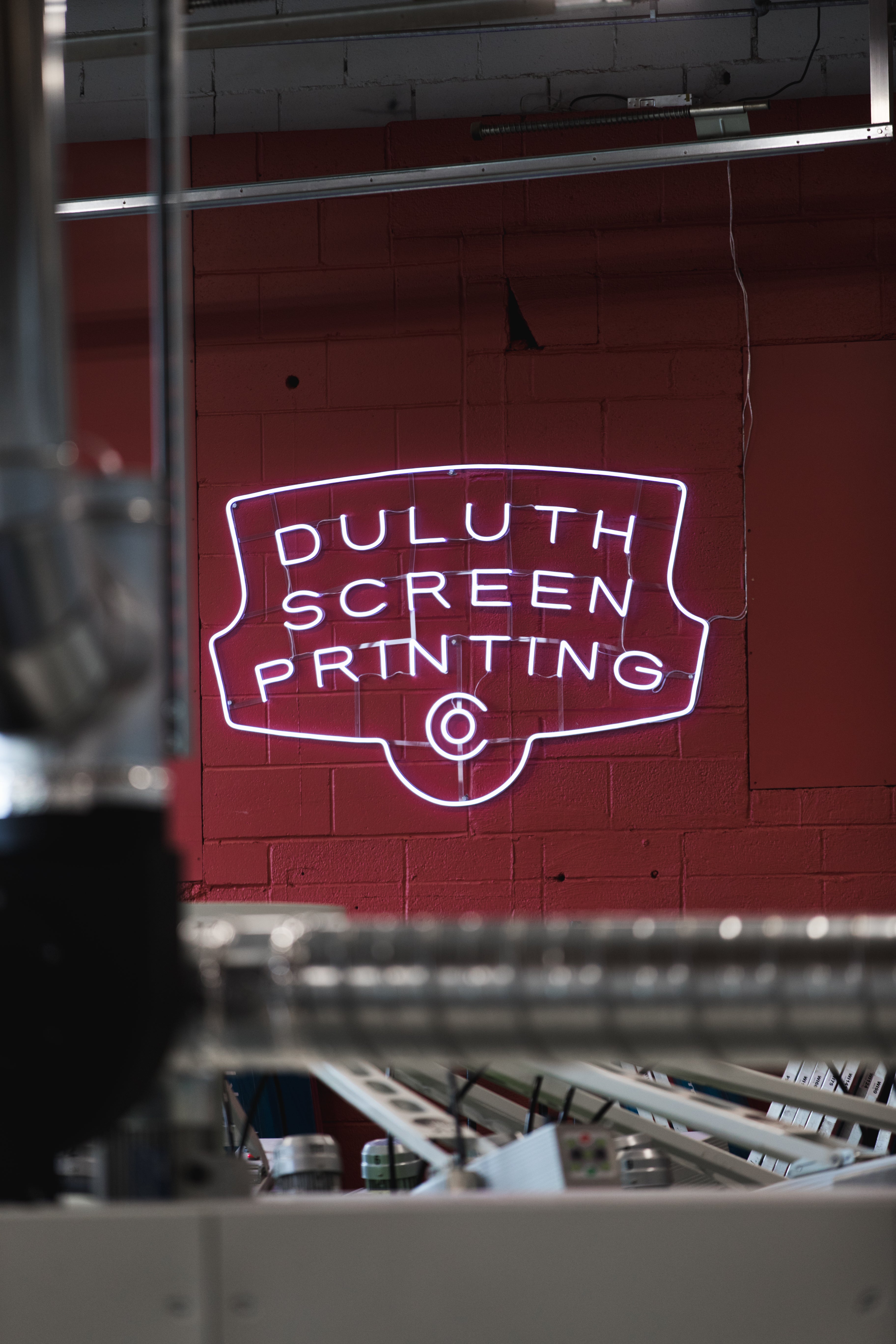 light up Duluth Screen Printing sign above screen printing press